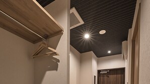 Un pasillo estrecho con un banco de madera, una puerta y una rejilla en el techo.