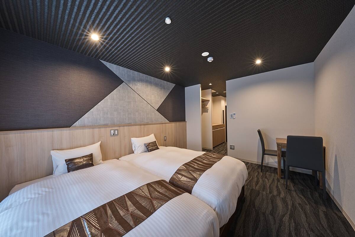 Une chambre d’hôtel moderne, dotée d’un grand lit, d’un bureau et d’une chaise.
