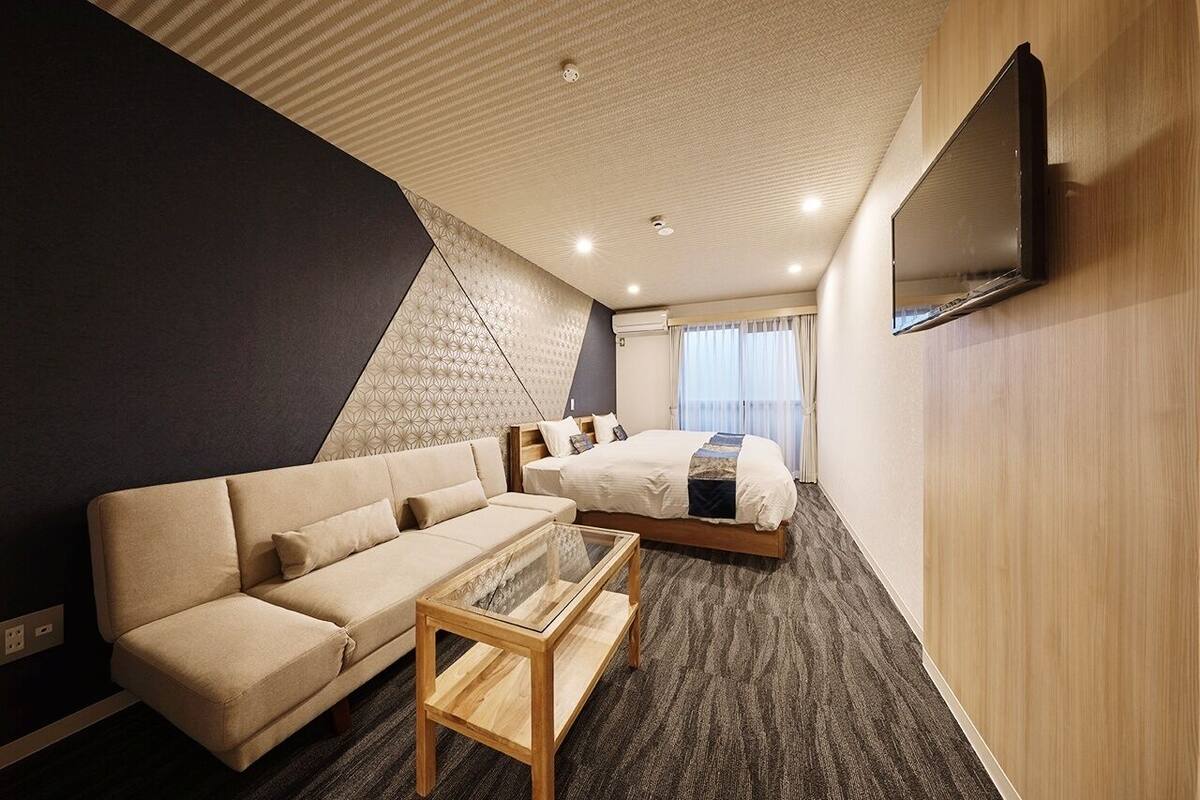 Une chambre d’hôtel avec un canapé, un lit, une télévision et un sol recouvert de moquette.