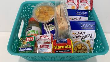 Ein blaugrünes Tablett mit verschiedenen Lebensmitteln, darunter Gläser mit Apfel-Orangen-Marmelade, Erdbeermarmelade, Erdnussbutter und verpacktem Brot.