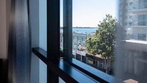 A view from a window overlooking a waterfront with buildings and a tree. - Quest Tauranga Central (Tauranga)