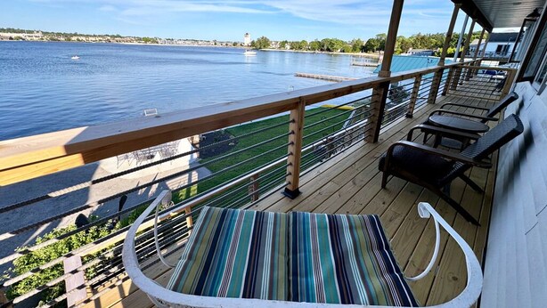 Une terrasse avec vue sur une étendue d’eau calme, une chaise longue et une petite table.