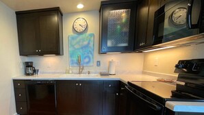 Moderni keittiö, jossa on tummat kaapit, ruostumattomasta teräksestä valmistettu liesi ja mikroaaltouuni.