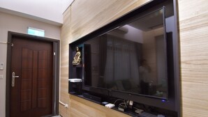 A modern interior with a large flat-screen TV mounted on a wooden wall, a dark wooden door, and a small statue on a shelf. - The 123 B&B (Ji'an)