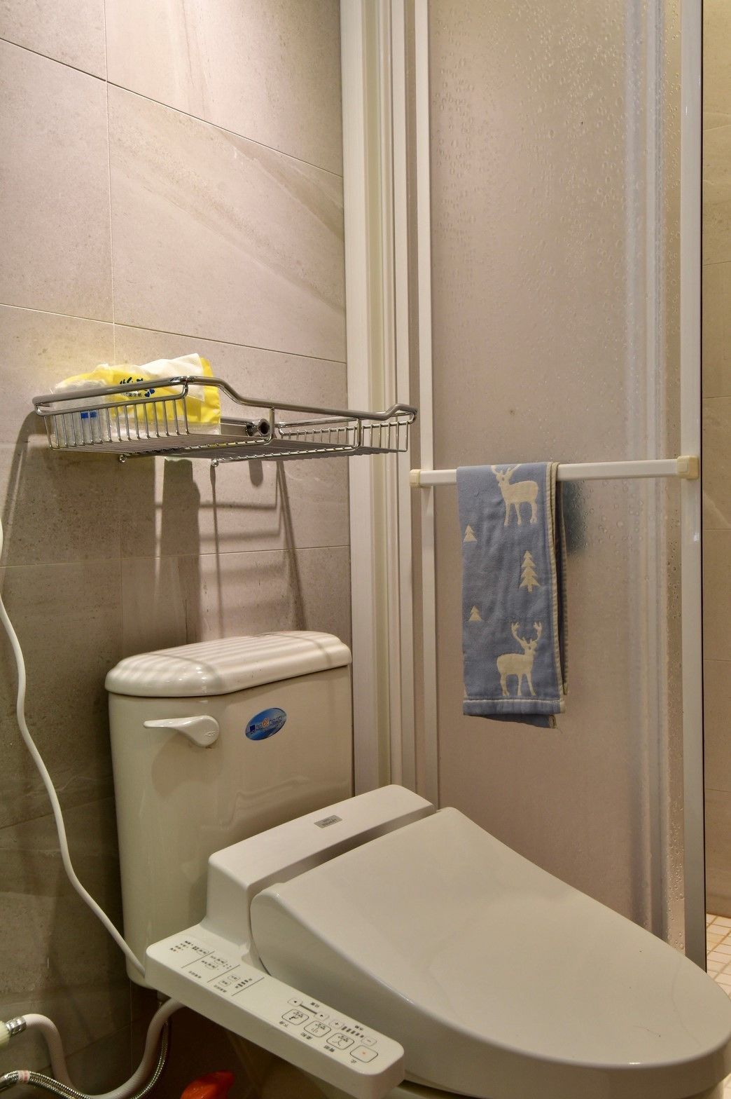 A bathroom with a toilet, a shower, and a towel rack with a towel.