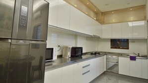 A modern kitchen with stainless steel appliances, white cabinetry, and a built-in oven. - The 123 B&B (Ji'an)