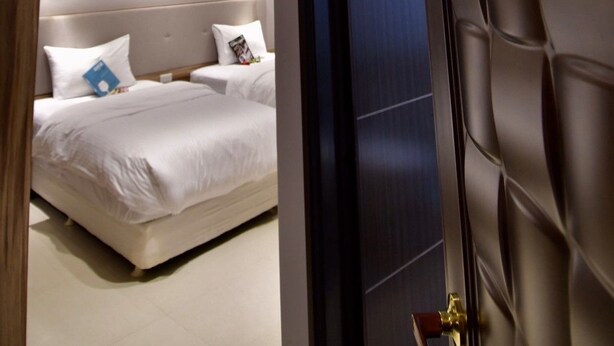A modern hotel room with a large bed, a headboard, and a door leading to another room. - The 123 B&B (Ji'an)