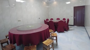 A conference room with a round table, red chairs, and wooden stools. - Lv ye Xian Zhuang Guesthouse (Taizhou)