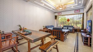 A spacious living room with a wooden dining table, benches, and a sofa. - Lv ye Xian Zhuang Guesthouse (Taizhou)