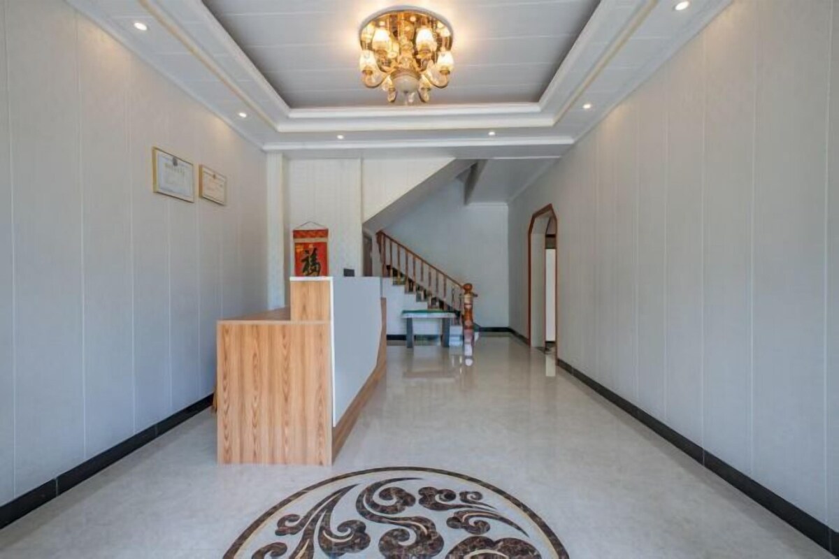 A hotel lobby with a reception desk, a staircase, and a decorative floor pattern.
