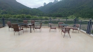 A terrace with a view of mountains and a river. - Lv ye Xian Zhuang Guesthouse (Taizhou)