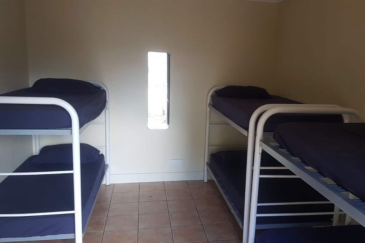 A room with bunk beds, a window, and tiled flooring.