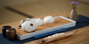 A wooden tray with white and brown containers, a blue napkin, and a decorative item on a table. - Wayn-Zen Onna Hotel (Onna)