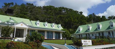 A hotel with a green roof, multiple windows, and a signboard.
