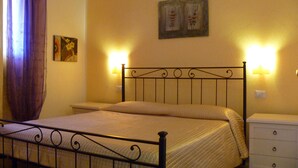 A bedroom with a bed, nightstand, wall-mounted lamps, and a painting. - Sardinia-Pittulongu-Holiday home w/ garden 5 min. walk from withe sandy beaches (Olbia)