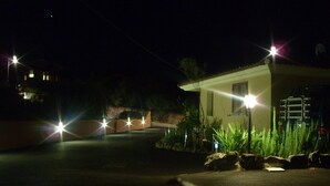 A nighttime view of a building with a small porch area, surrounded by rocks and plants. - Sardinia-Pittulongu-Holiday home w/ garden 5 min. walk from withe sandy beaches (Olbia)