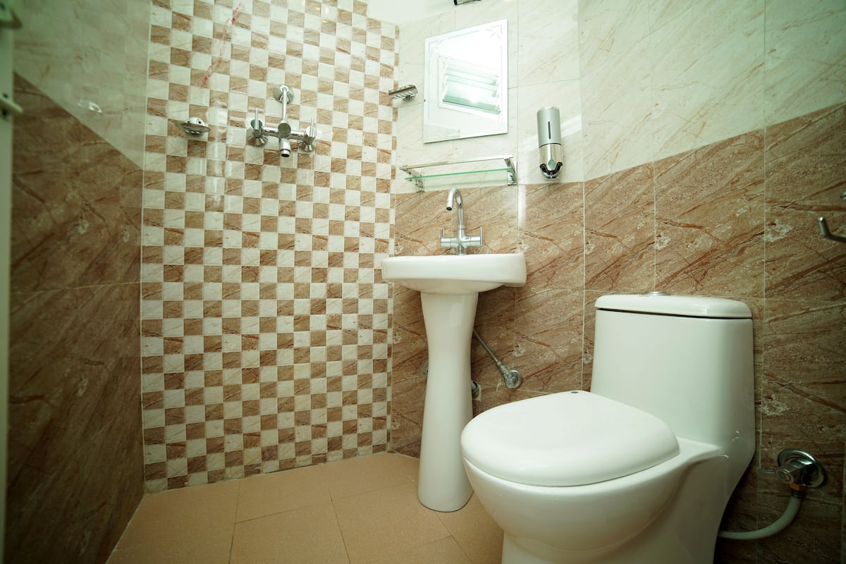 A bathroom with a checkered tile wall, a pedestal sink, and a toilet.