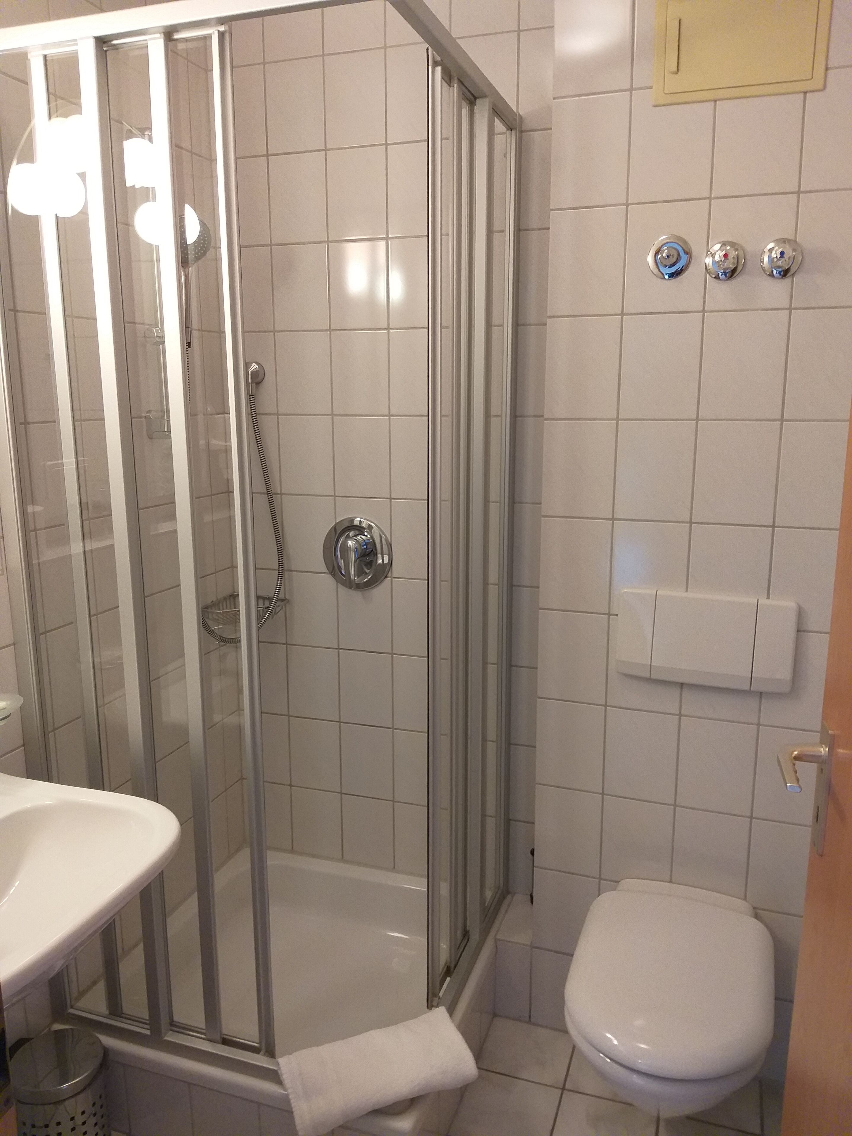 A bathroom with a glass-enclosed shower, a white sink, and a toilet.