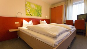 Une chambre d’hôtel avec un lit double, un bureau avec une chaise, une télévision et un tableau au mur.