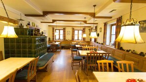 Un restaurant avec des tables et des bancs en bois, des lampes suspendues et un mur recouvert de carreaux verts.