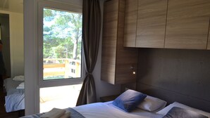 Une chambre d’hôtel avec un grand lit, une fenêtre avec des rideaux et des armoires en bois au-dessus du lit.