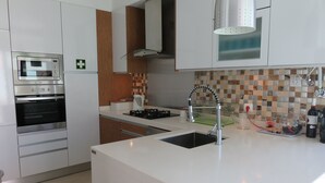 A modern kitchen with stainless steel appliances, a white countertop, and a tiled backsplash.