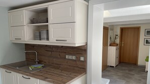 Eine kleine Küche mit weißen Schränken, einer Holz Arbeitsplatte und einer eingebauten Spüle.