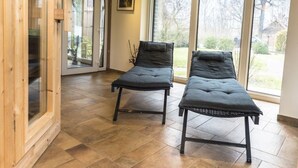 Ein Raum mit zwei Massagetischen, großen Fenstern und einer Holzinnenausstattung.