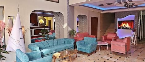 A spacious lobby with a blue sofa set, a small round table, and a fireplace.