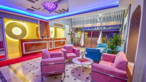 A hotel lobby with a reception desk, pink sofas, a coffee table, and a blue sofa. - Marina Hotel (Izmir)