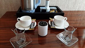 A breakfast setup with a coffee maker, two cups, two glasses, and some food items on a tray. - Marina Hotel (Izmir)