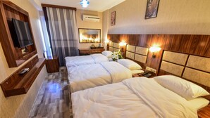 A hotel room with a large bed, a TV, a mirror, and a bedside table with a lamp. - Marina Hotel (Izmir)