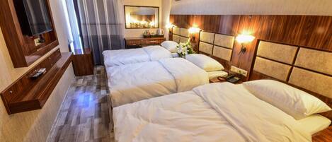 Una habitación de hotel con una cama grande, un televisor, un espejo y una mesita de noche con una lámpara.
