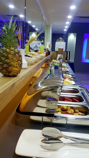 A buffet setup with various food items and utensils. - Marina Hotel (Izmir)
