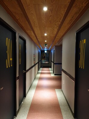 A hallway with doors numbered 304 and 307, wooden ceiling, and a carpeted floor. - Motel Good Guy (Pohang)