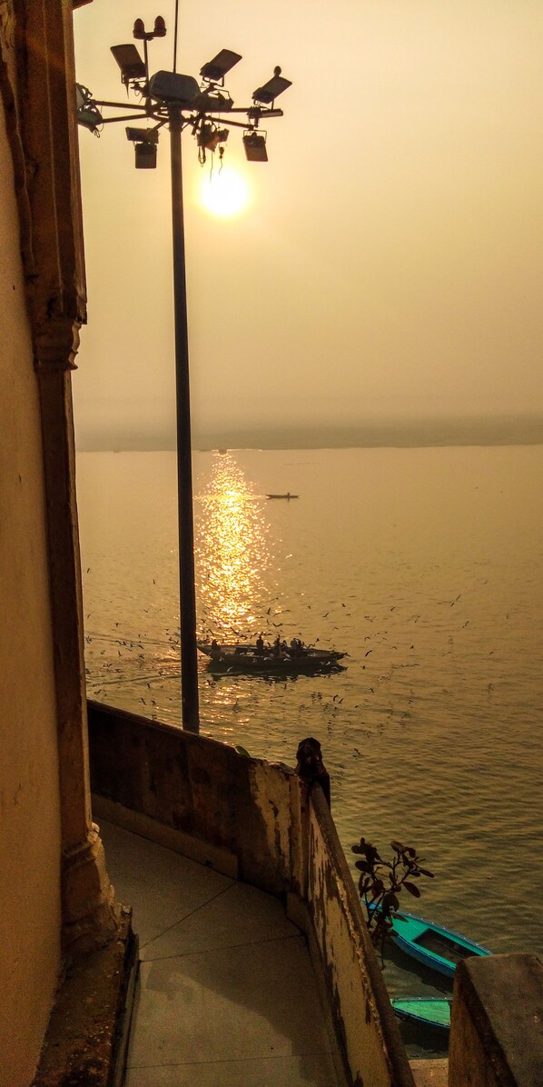 A staircase leading to a body of water with a boat and people in the distance. - Dwivedi Hotels Hotel Elena (Varanasi)
