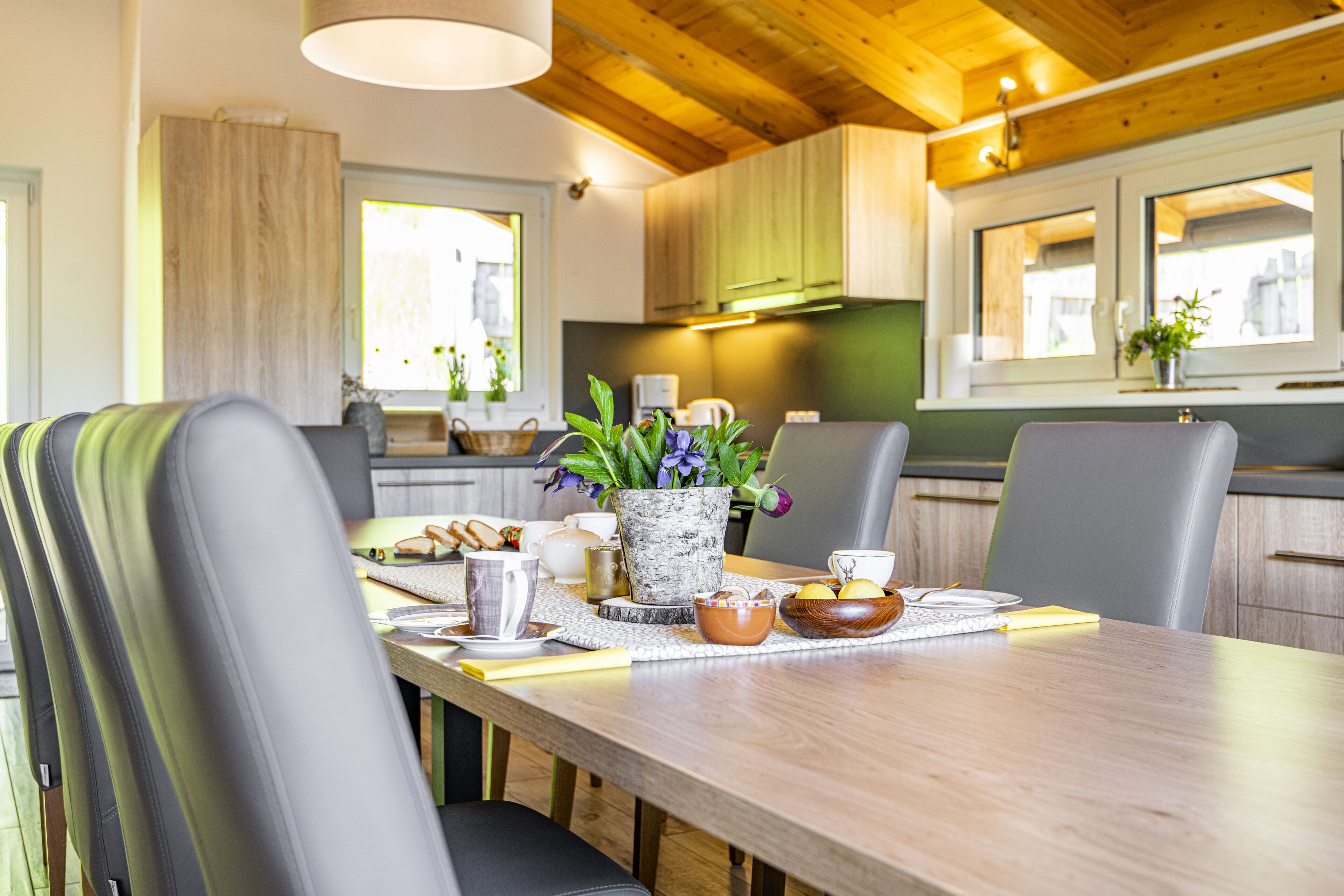 Une cuisine moderne avec des meubles en bois, une table à manger avec des chaises et une fenêtre donnant sur un beau paysage.