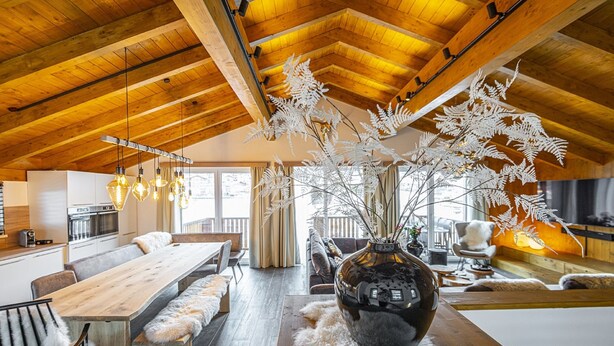 Un vaste espace de vie doté d’un plafond en bois, d’une grande table à manger en bois et d’un vase décoratif placé au centre.