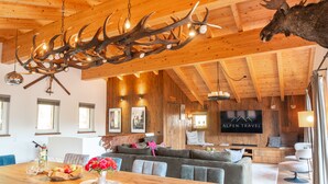 Un vaste espace de vie doté d’un plafond en bois, d’une grande table à manger et d’une tête de cerf fixée au mur.