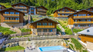 Un ensemble de bâtiments de style chalet en bois, dotés de balcons, d’une piscine et d’un mur de soutènement en pierre.