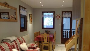 A cozy living room with a sofa, a dining table, and a staircase. - APPT. T 3 IN CHALET (Saint-Sorlin-d'Arves)