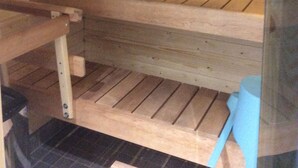 A sauna with wooden benches and a tiled floor. - Kotimaailma Apartments Siljotie (Rovaniemi)