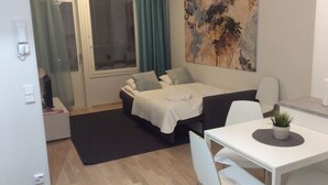 A modern, well-lit room with a bed, a desk, and a large abstract painting on the wall. - Kotimaailma Apartments Siljotie (Rovaniemi)