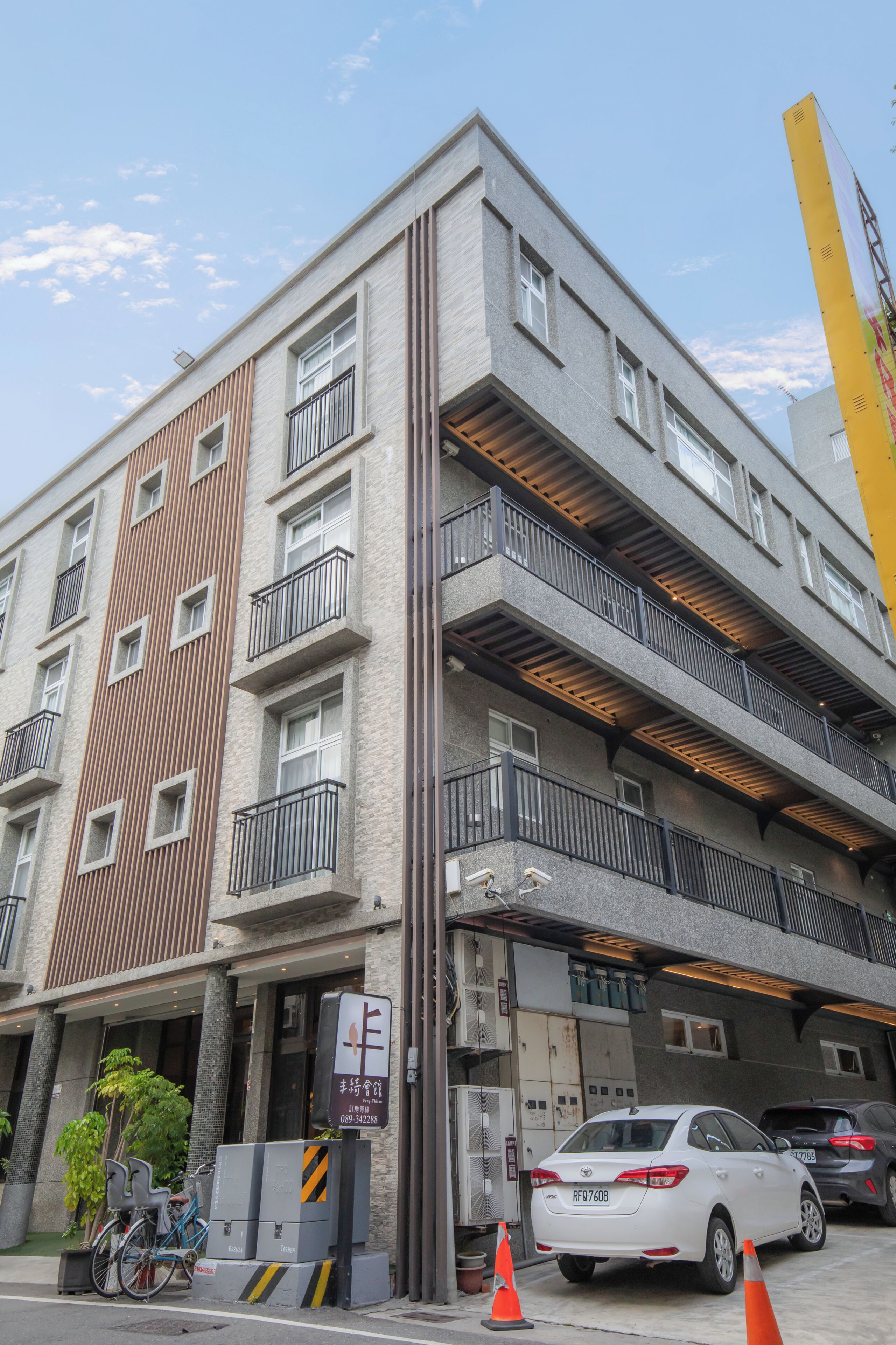 A multi-story building with balconies, a parking area, and a bicycle.
