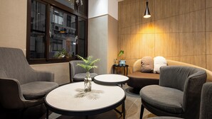 Ein moderner Lounge-Bereich mit einer Couch, Sesseln, einem kleinen Tisch und einer Zimmerpflanze.
