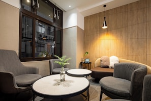 A modern lounge area with a sofa, armchairs, a small table, and a potted plant. - Feng Chi Inn (Taitung)