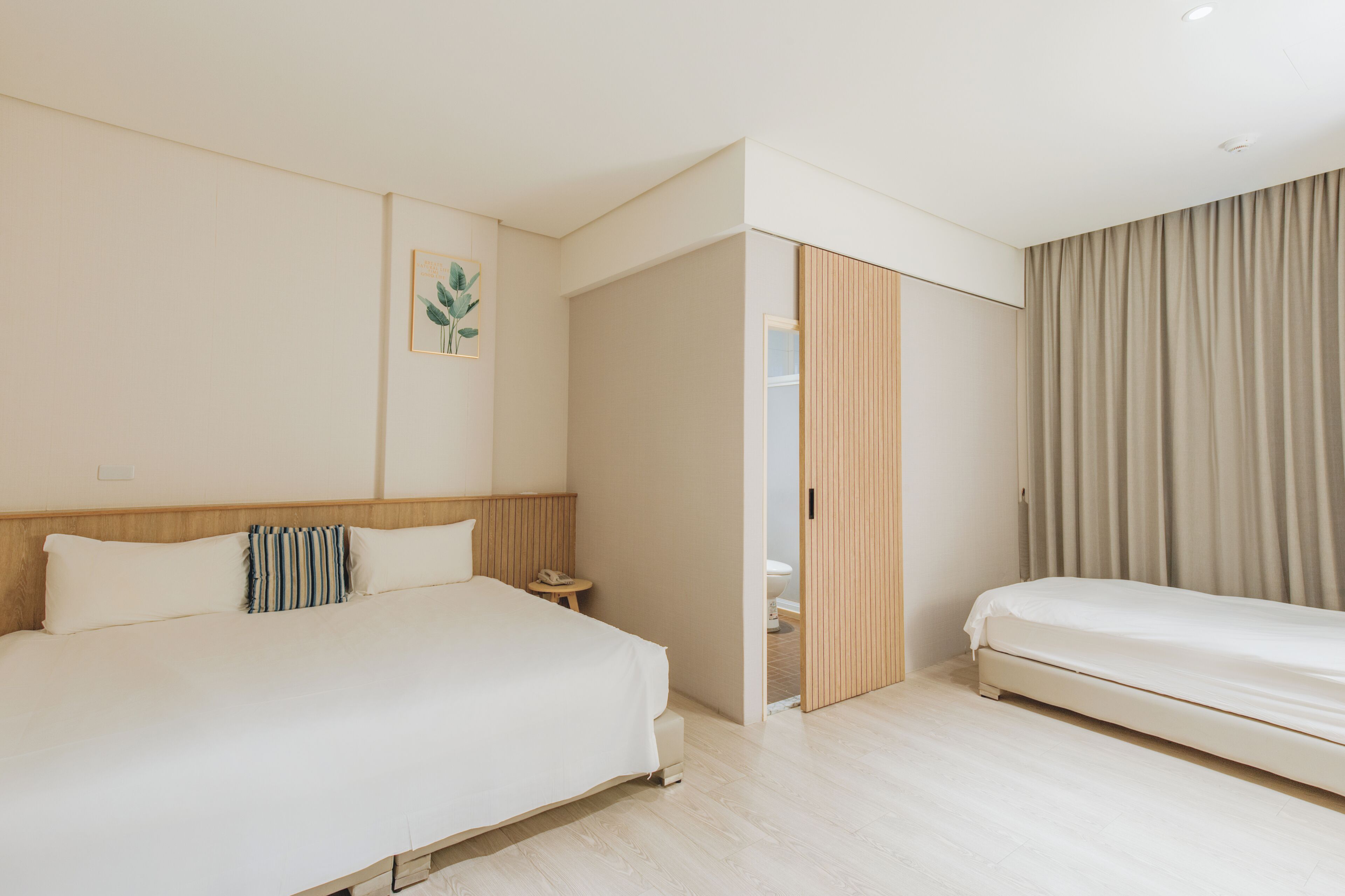 A hotel room with a bed, bedside table, and a door leading to a bathroom.