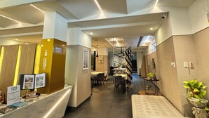 Eine moderne Hotelhalle mit Empfangstresen, Sitzgelegenheiten und einer Treppe zu den oberen Etagen.
