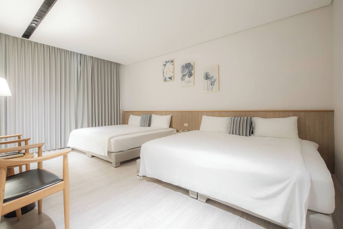 A hotel room with two beds, a desk, and a chair.