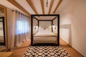 A bedroom with a four-poster bed, a large mirror, and a patterned rug.